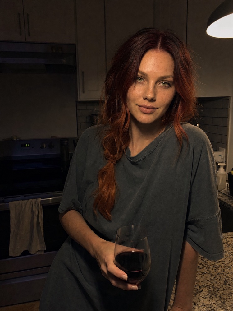 Woman with a glass of wine in a kitchen, generated with the fixed prompt